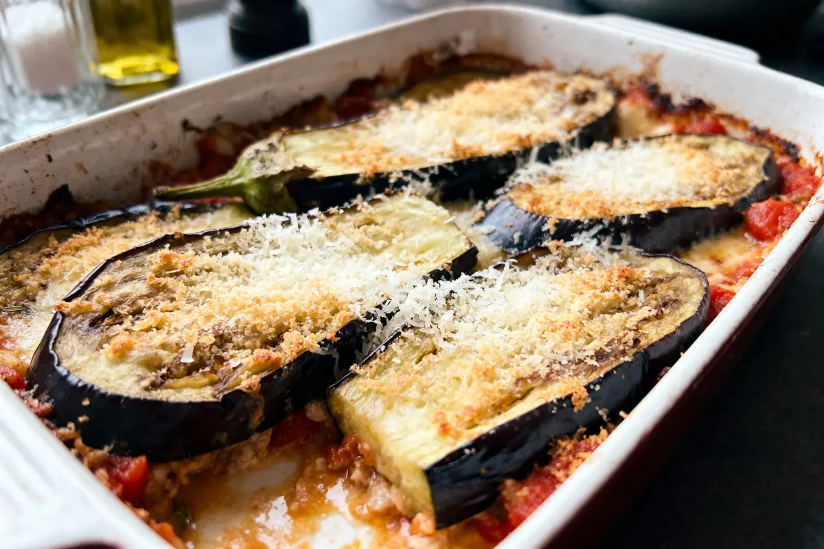 Gratin d'aubergines avec fromage râpé dans un plat en céramique rectangulaire.