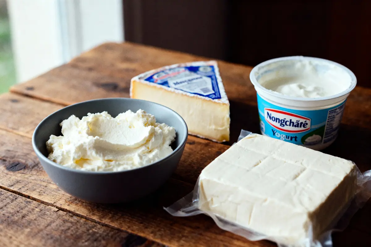 Assortiment de produits laitiers : fromage, yaourt, crème, sur une table en bois.