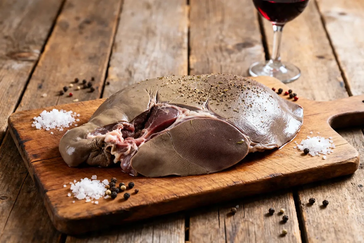 Foie frais prêt pour foie gras maison sur planche en bois avec sel et poivre
