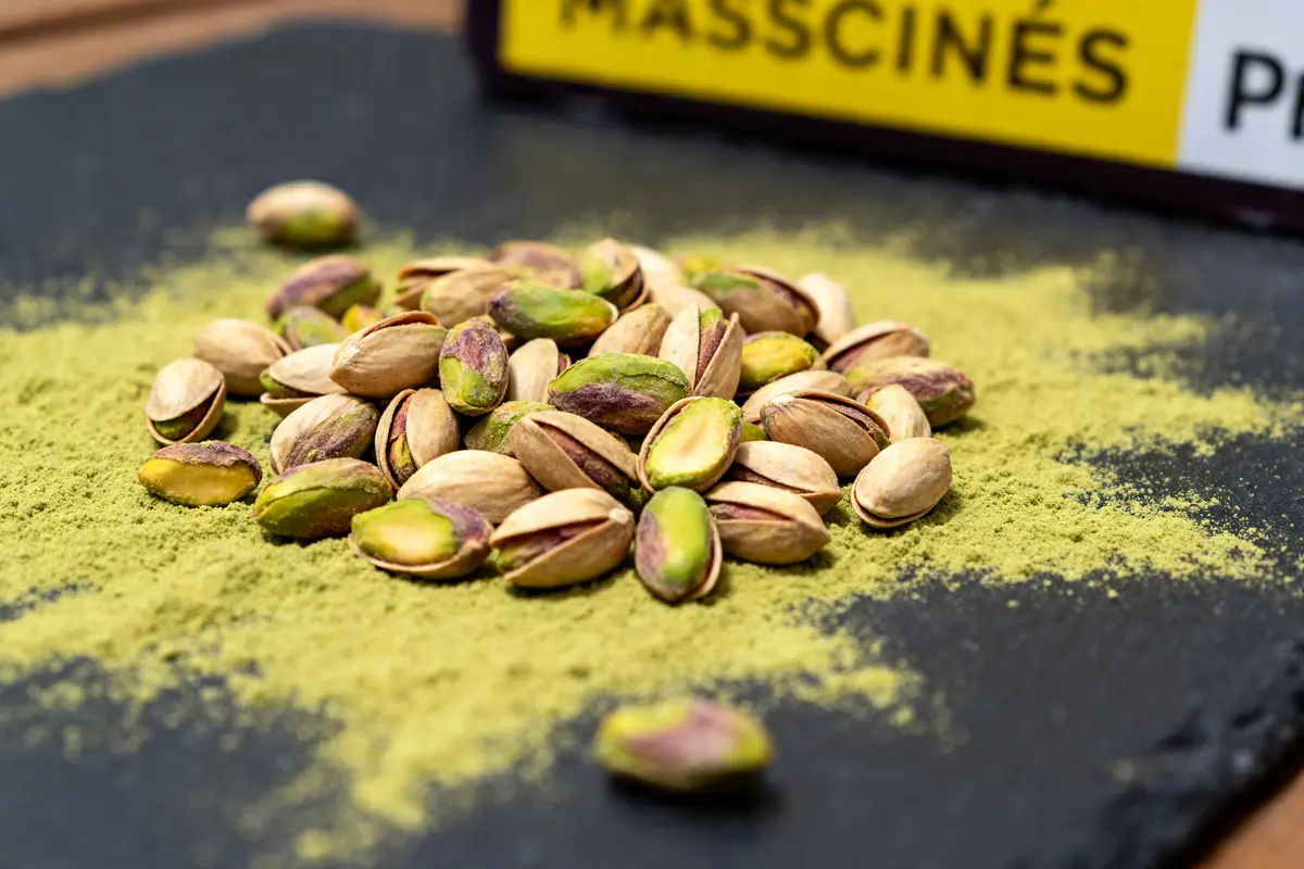 Pistaches éparpillées sur poudres de pista et pistachio sur une ardoise noire