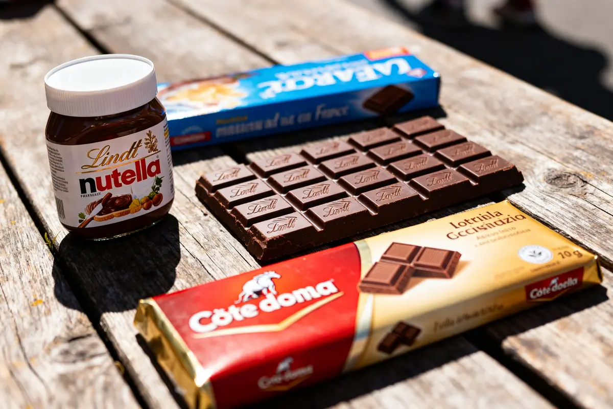 Table en bois avec différentes marques de chocolat, y compris tablettes et pâte à tartiner.