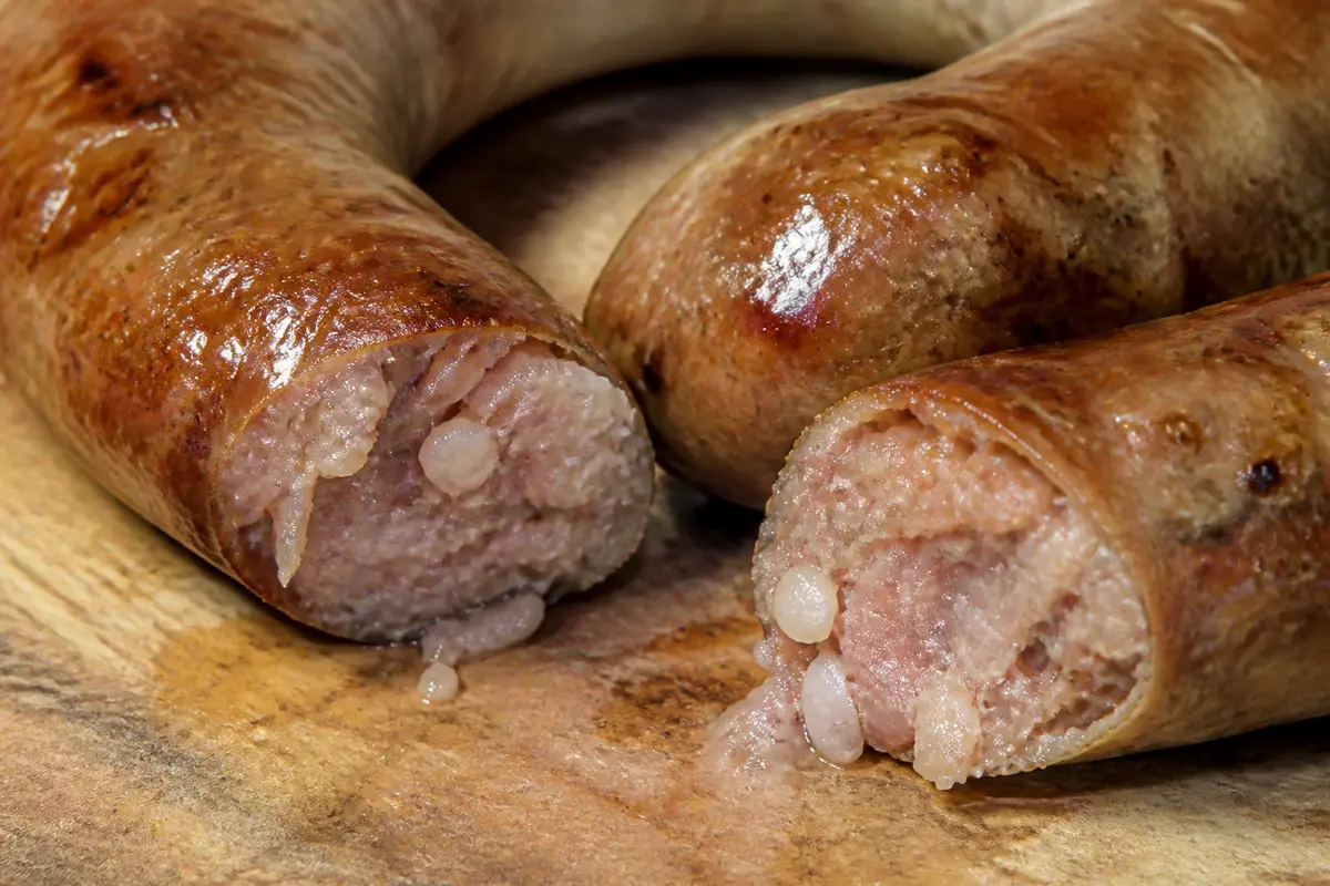 Gros plan d'une saucisse de couenne coupée en deux sur une planche en bois