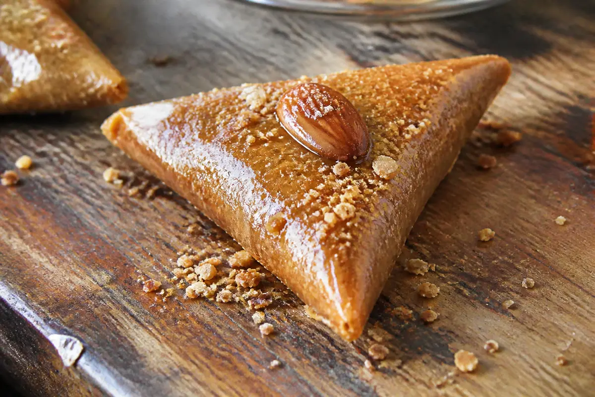 Pâtisserie orientale, triangle aux amandes caramélisées posé sur une table en bois rustique